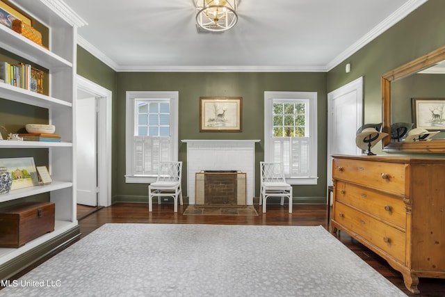 living area with crown molding, baseboards, a brick fireplace, and wood finished floors