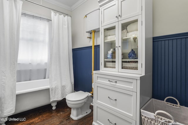 bathroom with wainscoting, wood finished floors, toilet, shower / tub combo with curtain, and ornamental molding