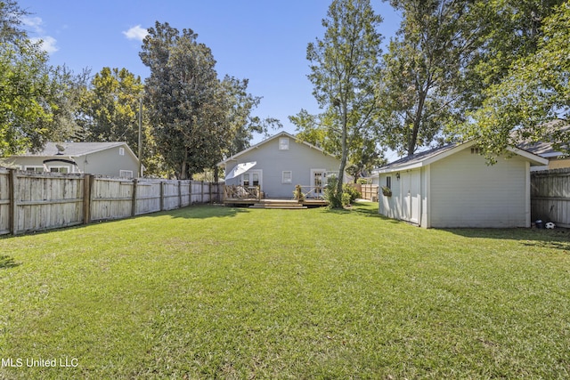 view of yard with a fenced backyard, a wooden deck, an outbuilding, and a shed
