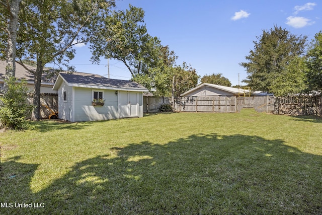 view of yard with an outdoor structure, a fenced backyard, and a shed