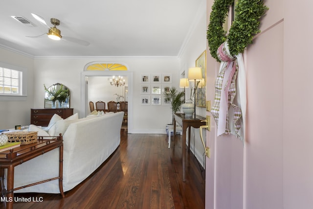 living area featuring visible vents, crown molding, ceiling fan with notable chandelier, and dark wood-style floors