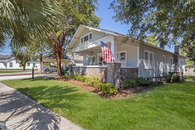 view of home's exterior with covered porch and a lawn