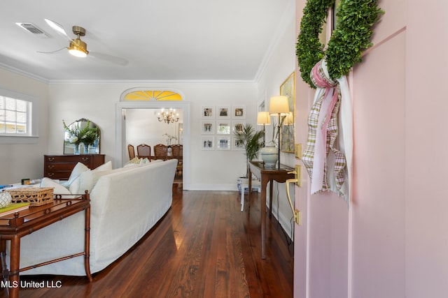 living room featuring ornamental molding, dark wood-type flooring, and ceiling fan with notable chandelier