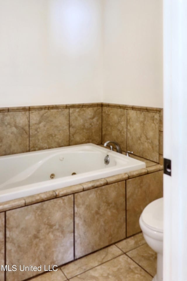 bathroom featuring tile patterned floors, toilet, and tiled bath