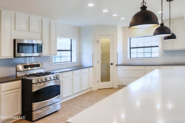 kitchen featuring decorative backsplash, decorative light fixtures, white cabinetry, light tile patterned floors, and appliances with stainless steel finishes