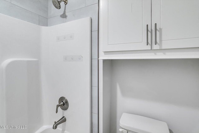 bathroom featuring toilet and tiled shower / bath