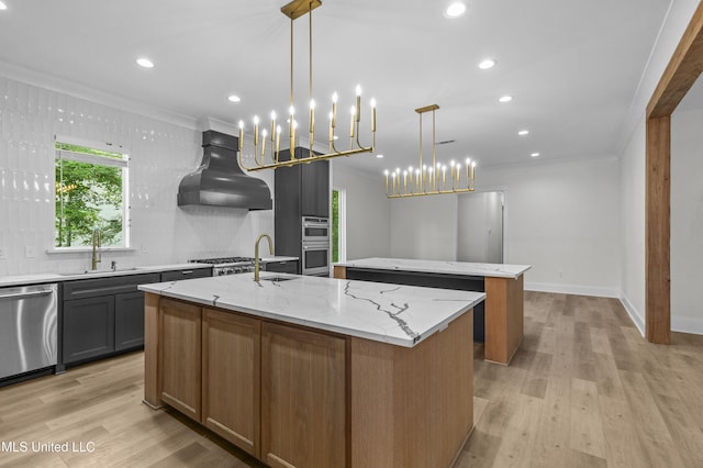 104 Westlake Cir W, Madison, MS 39110 - kitchen featuring an island with sink, appliances with stainless steel finishes, wall chimney range hood, crown molding, and light wood-style floors