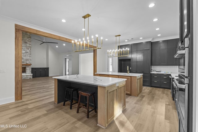 104 Westlake Cir W, Madison, MS 39110 - kitchen with a large island with sink, decorative backsplash, light wood-style flooring, recessed lighting, and decorative light fixtures