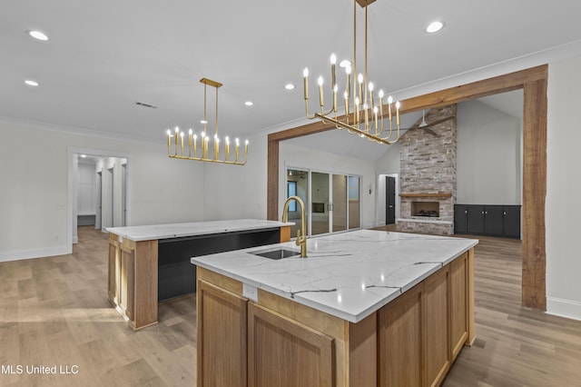 104 Westlake Cir W, Madison, MS 39110 - kitchen featuring an island with sink, light wood-style floors, recessed lighting, light stone counters, and a stone fireplace
