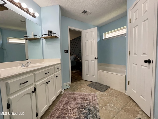5306 Kristy Ln, Southaven, MS 38671 - ensuite bathroom featuring vanity, a bath, a textured ceiling, and tile patterned floors