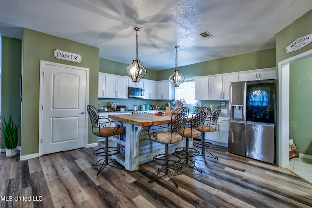 kitchen featuring wooden counters, pendant lighting, stainless steel appliances, and white cabinets