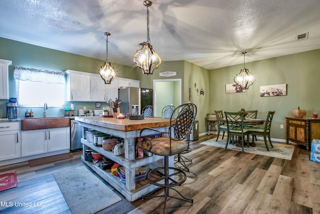 kitchen featuring light hardwood / wood-style floors, pendant lighting, sink, white cabinetry, and appliances with stainless steel finishes