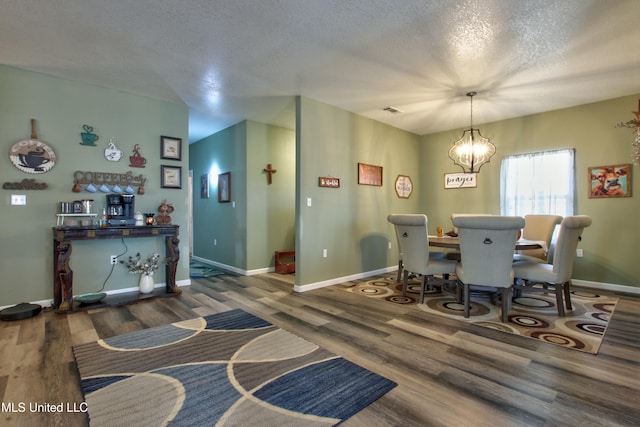 dining area featuring an inviting chandelier, a textured ceiling, and dark hardwood / wood-style floors