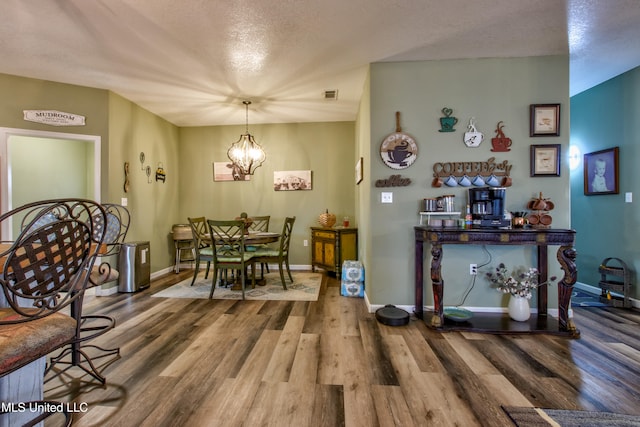 dining area featuring a textured ceiling, hardwood / wood-style flooring, and a notable chandelier