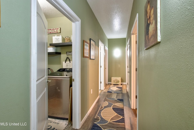 corridor featuring hardwood / wood-style floors, a textured ceiling, and washing machine and clothes dryer