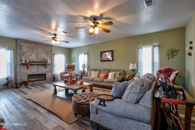 living room with hardwood / wood-style flooring, ceiling fan, a healthy amount of sunlight, and a textured ceiling