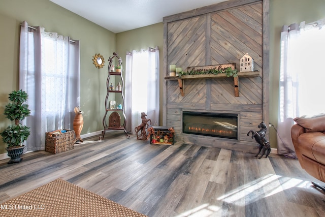 living room with hardwood / wood-style floors, a large fireplace, and a healthy amount of sunlight