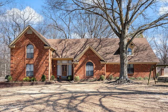 view of front facade with a shingled roof and brick siding