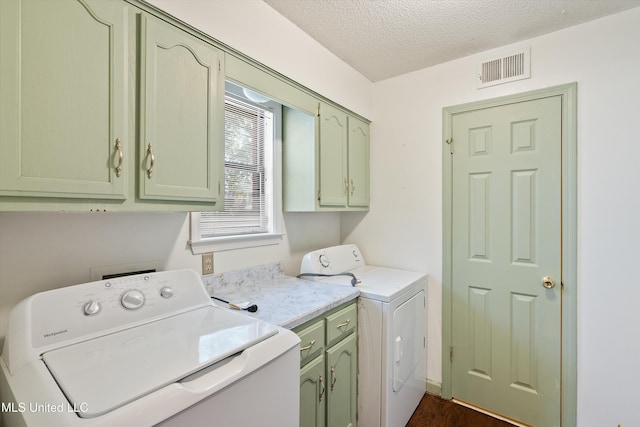 laundry room with visible vents, cabinet space, a textured ceiling, and washing machine and clothes dryer