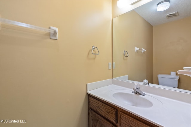 half bath with toilet, vanity, and visible vents