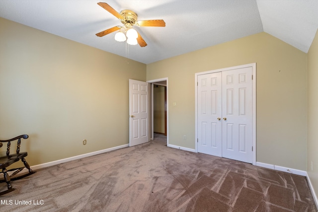 unfurnished bedroom with lofted ceiling, a closet, a ceiling fan, carpet flooring, and baseboards