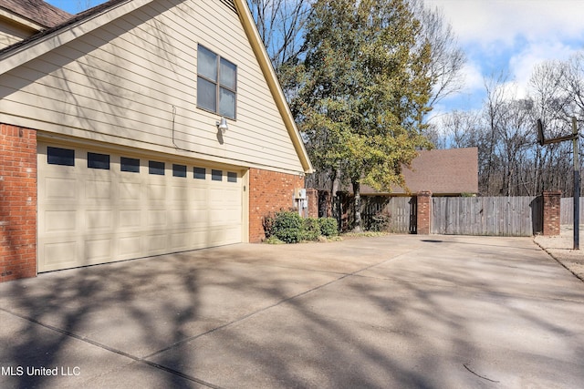 view of front facade featuring driveway, brick siding, and fence