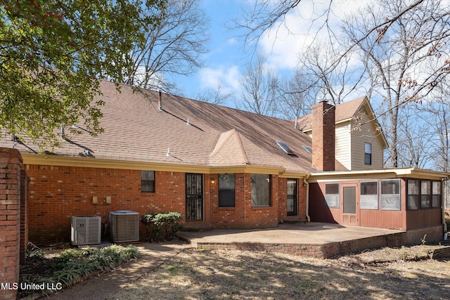 back of property with a patio area, central AC unit, a sunroom, and brick siding