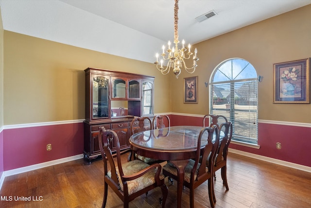 dining space with a chandelier, visible vents, baseboards, and hardwood / wood-style flooring