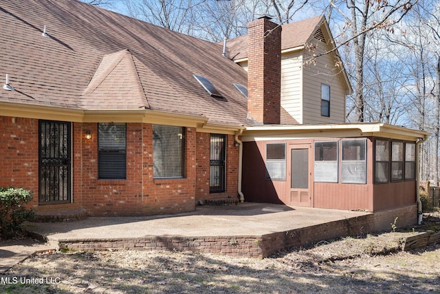 back of property with a patio, brick siding, a chimney, and a sunroom