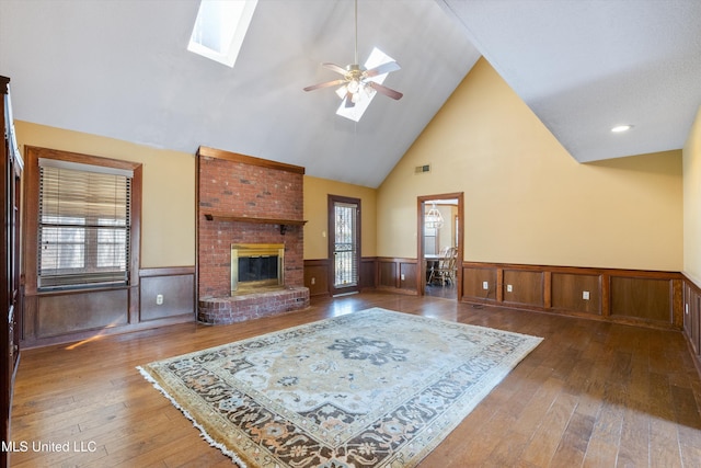 living area featuring a skylight, wood-type flooring, wainscoting, and a fireplace