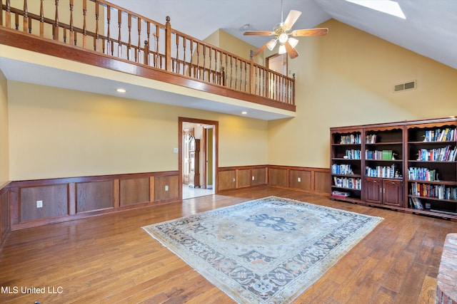 interior space featuring ceiling fan, wainscoting, wood-type flooring, and visible vents