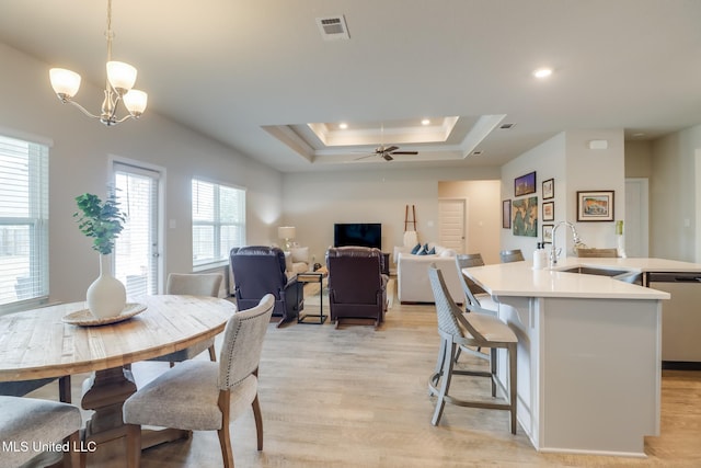 interior space featuring sink, ceiling fan with notable chandelier, light hardwood / wood-style floors, and a tray ceiling