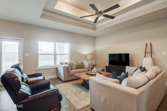 living room featuring a raised ceiling, crown molding, hardwood / wood-style floors, and ceiling fan