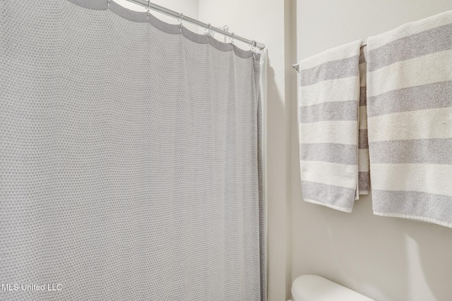 bathroom featuring a shower with shower curtain and toilet