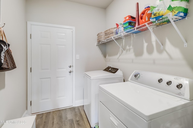 clothes washing area featuring washing machine and clothes dryer and light hardwood / wood-style flooring