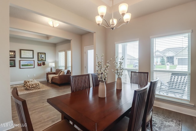 dining space with dark hardwood / wood-style flooring, a notable chandelier, and a healthy amount of sunlight