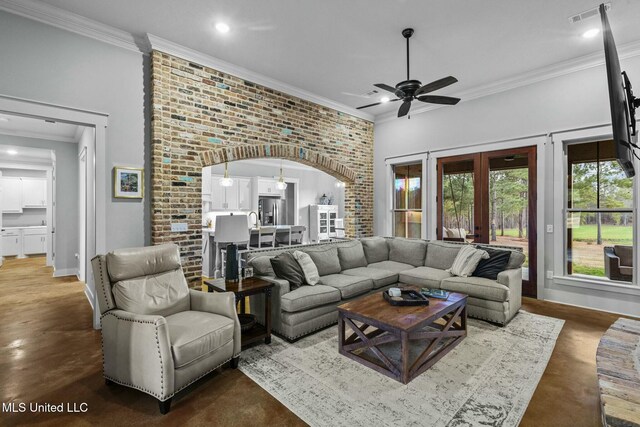 living room with crown molding, ceiling fan, brick wall, and french doors