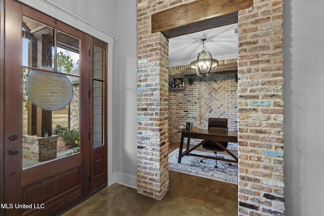 foyer featuring a notable chandelier, ornamental molding, and brick wall