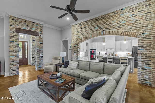 living room with ceiling fan, ornamental molding, brick wall, and concrete floors