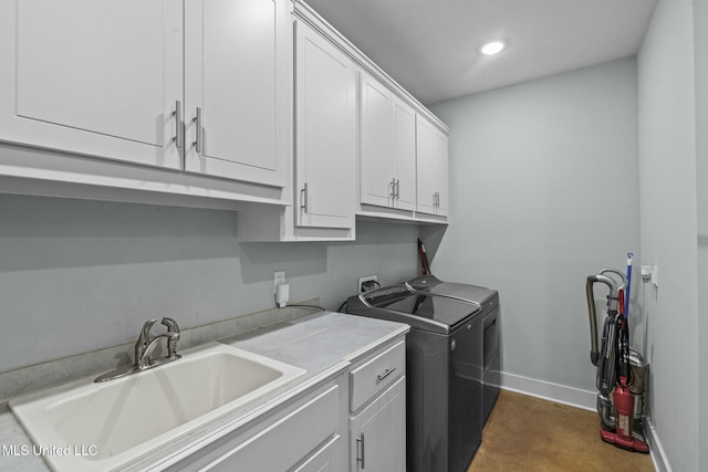 clothes washing area with cabinets, washing machine and dryer, and sink