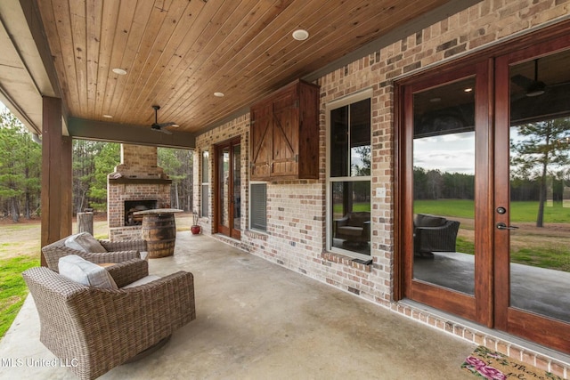 view of patio with an outdoor brick fireplace, ceiling fan, and french doors