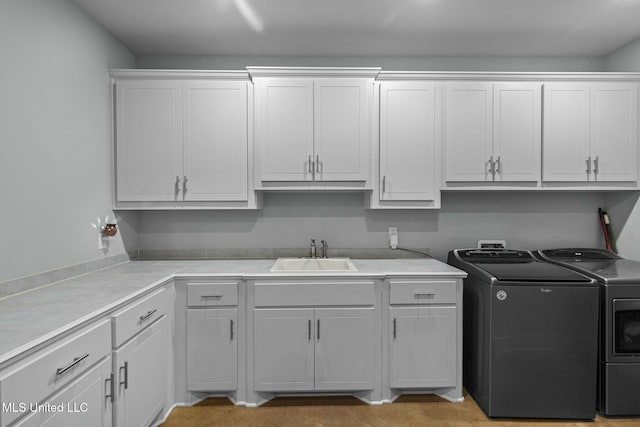 washroom with cabinets, independent washer and dryer, and sink