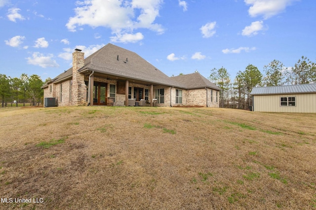 rear view of property with central AC unit and a lawn