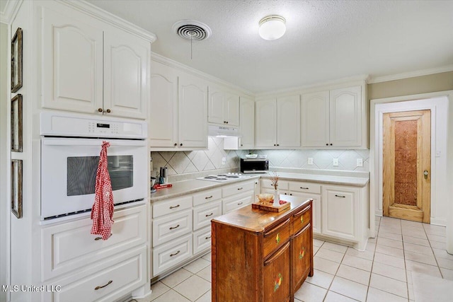 12661 Springridge Rd, Terry, MS 39170 - kitchen featuring white appliances, light tile patterned flooring, decorative backsplash, white cabinets, and crown molding
