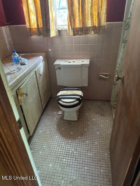 3411 25th Ave, Meridian, MS 39305 - bathroom with toilet, a wainscoted wall, tile walls, and tile patterned floors