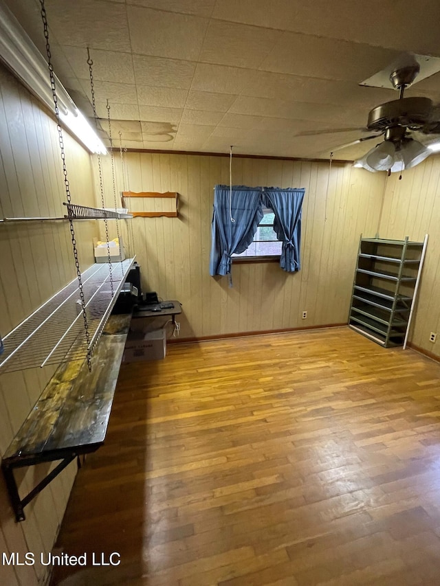 basement with wood walls, hardwood / wood-style floors, and ceiling fan