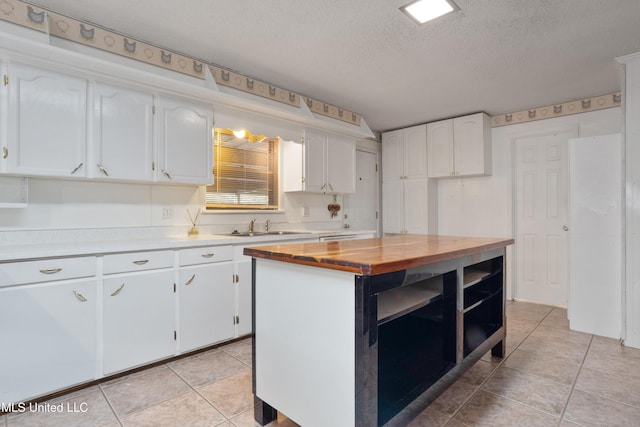 14071 Duckworth Rd, Gulfport, MS 39503 - kitchen with wooden counters, white cabinetry, a sink, light tile patterned floors, and a textured ceiling