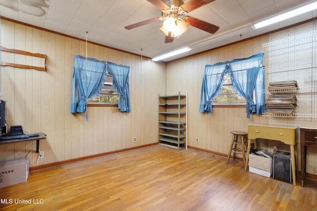 miscellaneous room with wooden walls, crown molding, ceiling fan, and wood-type flooring