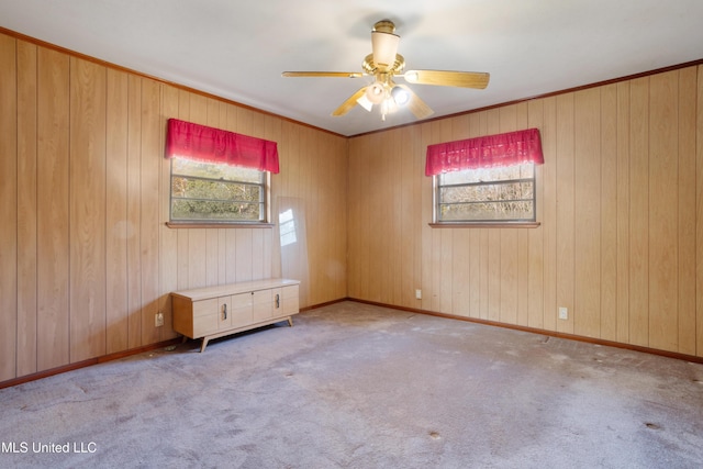 carpeted empty room featuring wood walls and ceiling fan