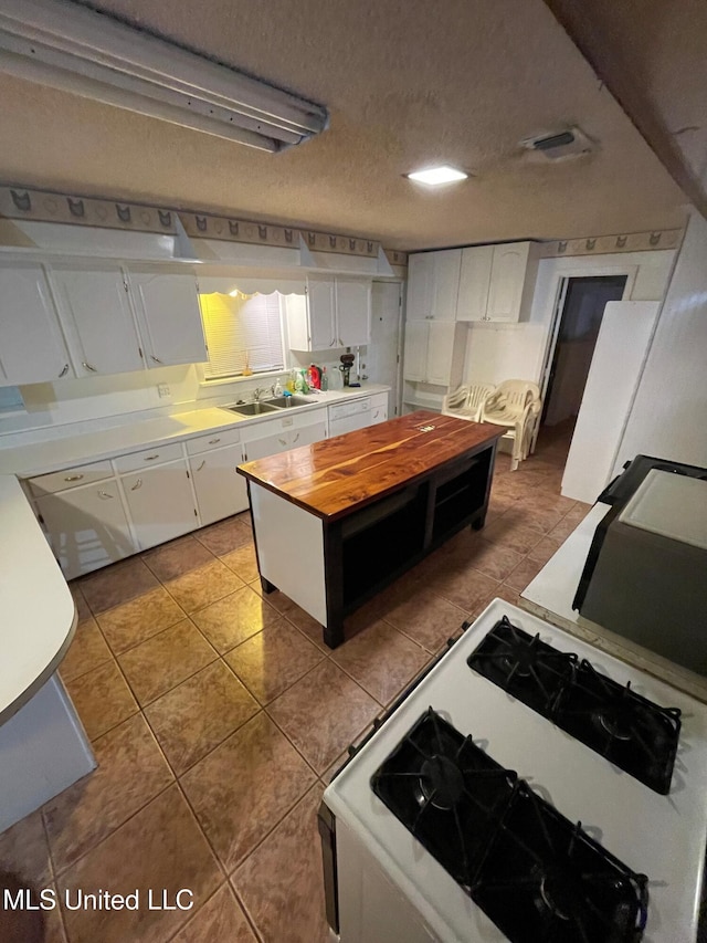 kitchen featuring white cabinets, sink, tile patterned floors, and a textured ceiling